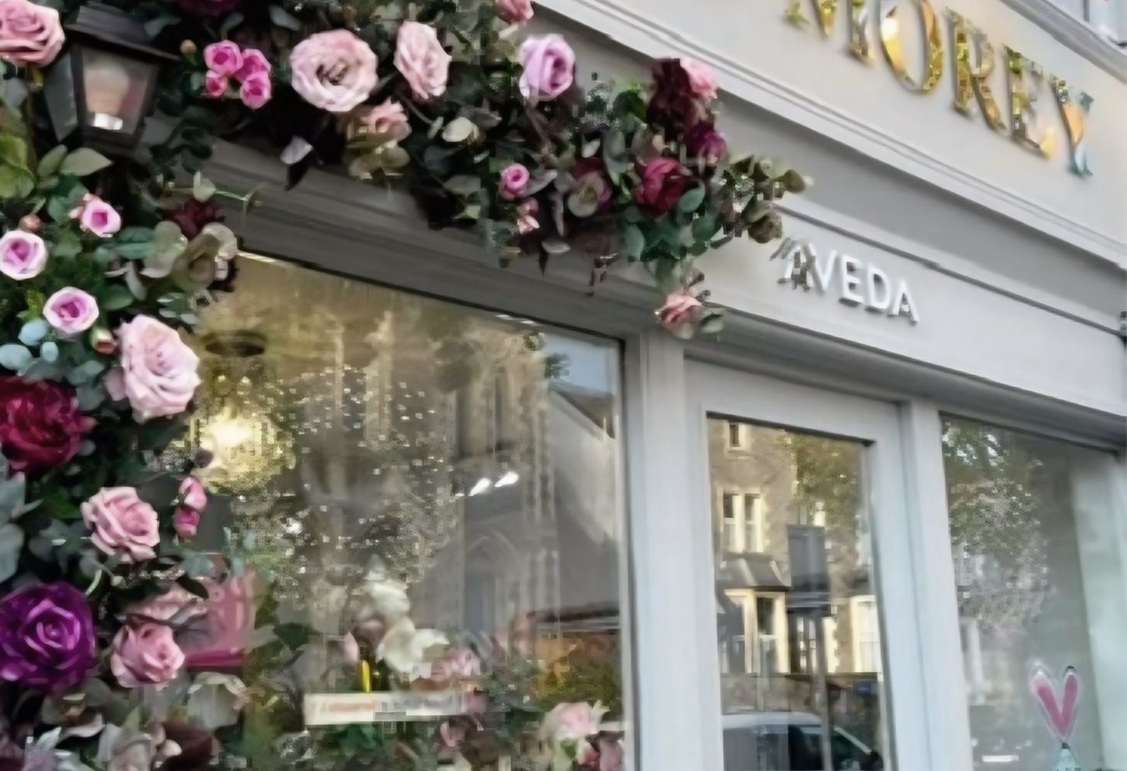 The Nuala Morey shopfront on Gloucester Road: dove-grey paintwork, gold lettering and an arch of pink and plum roses around the window